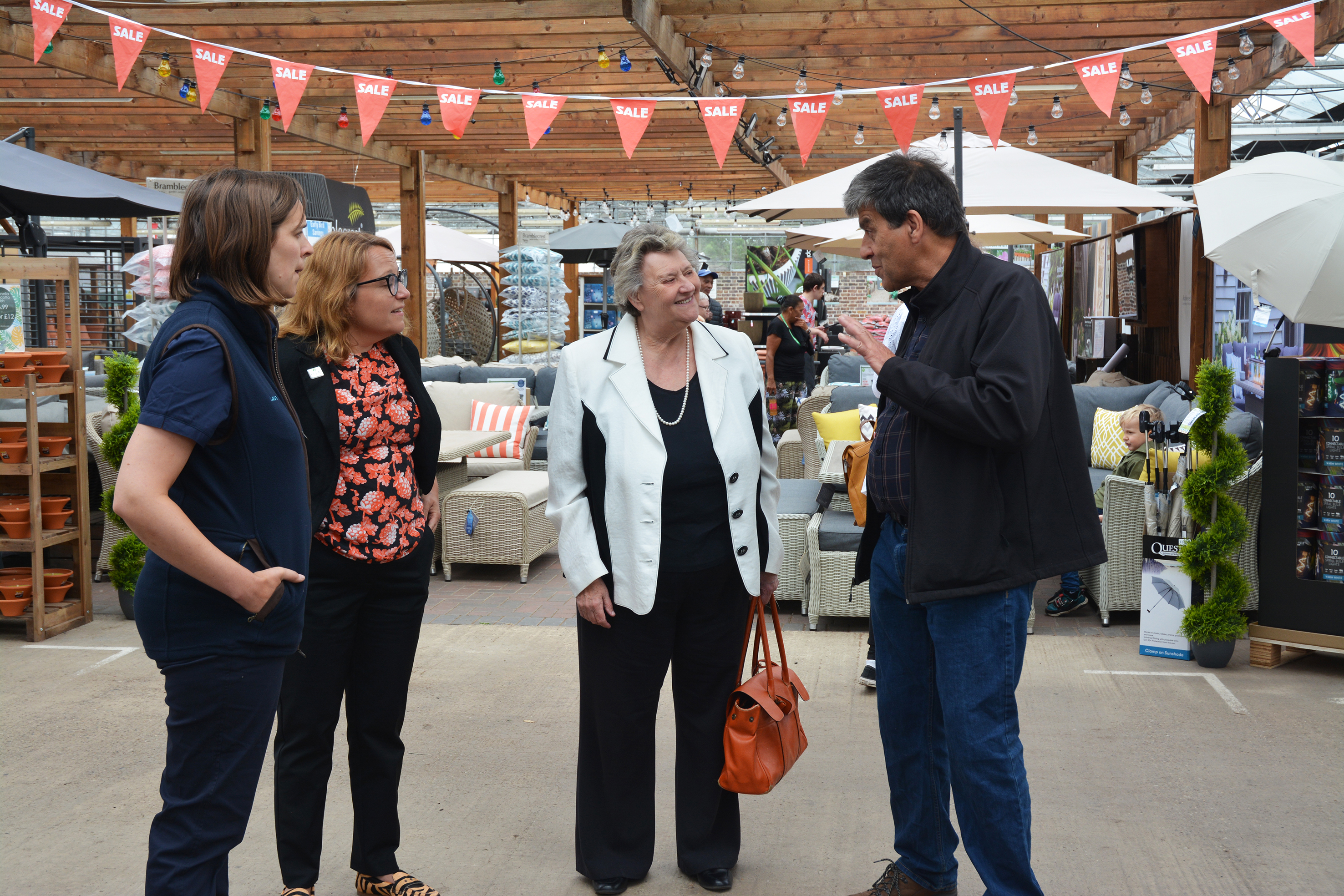 L-R Laura Jackson, Jennifer Pheasey, Heather Wheeler MP and John Jackson standing in a garden centre in front of a furniture display